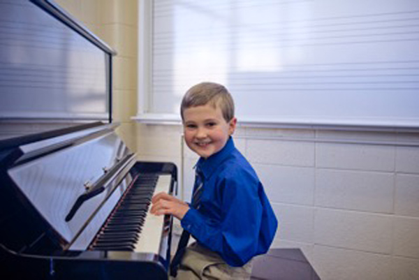 student smiling at camera from piano